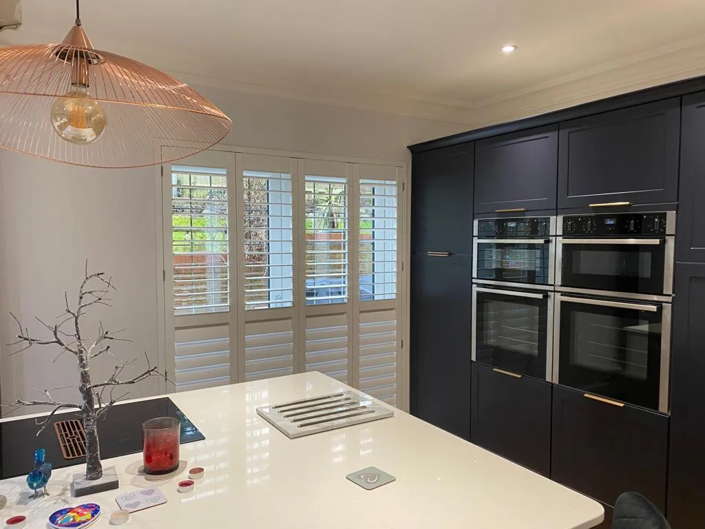 Full height shutters in a modern kitchen with dark blue cabinetry and a kitchen island