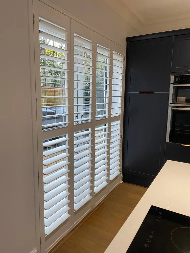 Full height white plantation shutters in a modern kitchen.
