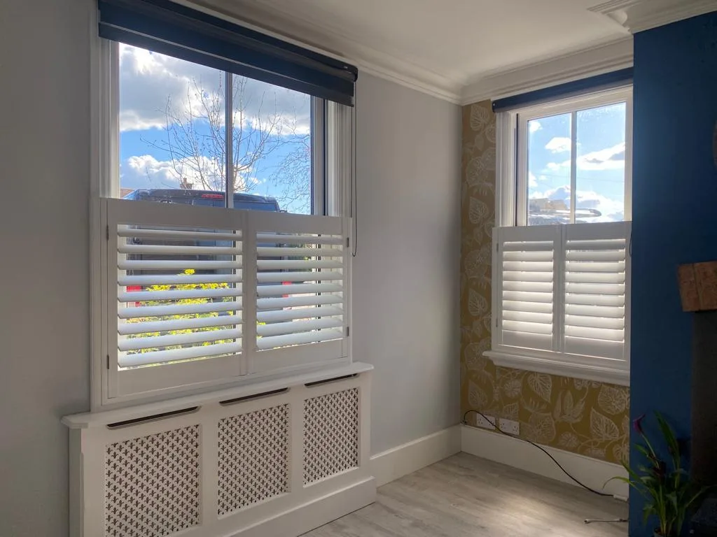 Café Style shutters in a living room with patterned wallpaper and a blue accent wall.
